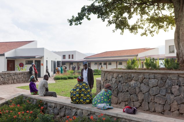 Photo of Butaro District Hospital, Photo by Iwan Baan, Visitors gather on a stone bench near the hospital