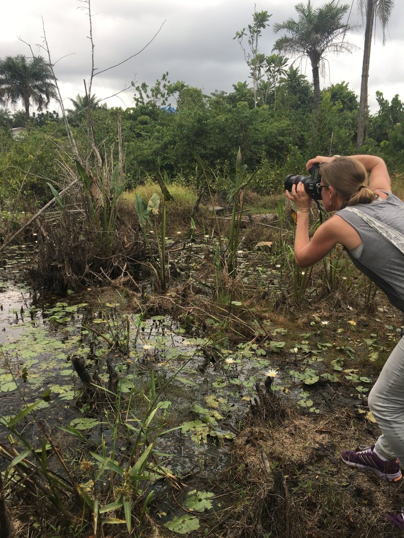 Image of Sierra on a site visit, taking a photo of marshlands